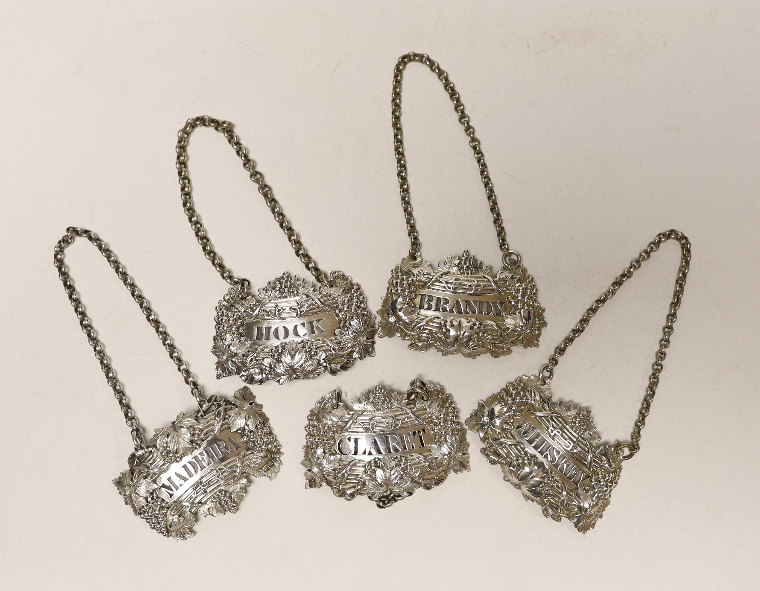 A matched set of five early 19th century ornate silver fruiting vine wine labels, Emes & Barnard, London, 1825/1827(2), Reily & Storer 1829 and 1850(2), width 6cm.